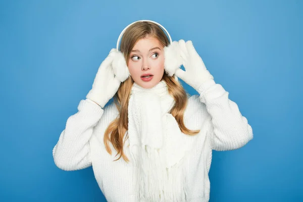 Здивована красива жінка в зимовому білому вбранні ізольована на синьому — стокове фото