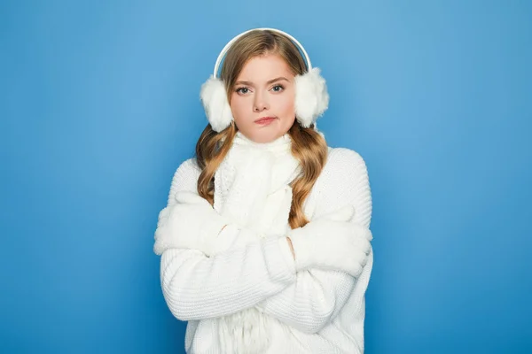 Schöne Frau im winterweißen Outfit fühlt sich kalt isoliert auf blau — Stockfoto