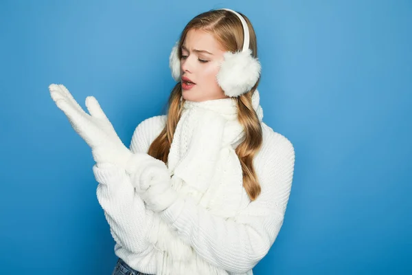 Bella donna in abito bianco invernale mettendo guanti isolata sul blu — Foto stock