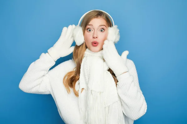 Mujer hermosa sorprendida en traje blanco de invierno aislado en azul - foto de stock