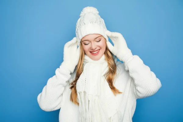 Sonriente hermosa mujer en invierno traje blanco aislado en azul - foto de stock