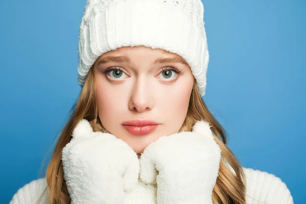 Portrait of sad beautiful woman in winter white outfit isolated on blue — Stock Photo