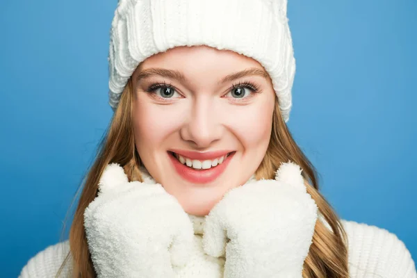 Портрет улыбающейся красивой женщины в зимнем белом наряде, изолированном на голубом — стоковое фото