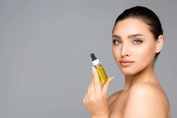Woman holding bottle with serum isolated on grey — Stock Photo