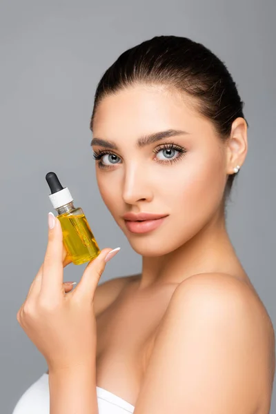 Woman holding bottle with serum isolated on grey — Stock Photo