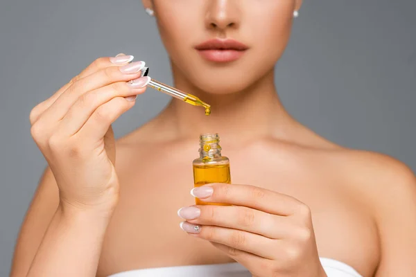 Cropped view of woman holding bottle with serum isolated on grey — Stock Photo