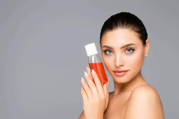 Belle femme avec bouteille de lotion isolée sur gris — Photo de stock