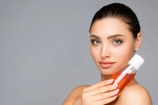 Schöne Frau mit Flasche Lotion isoliert auf grau — Stockfoto