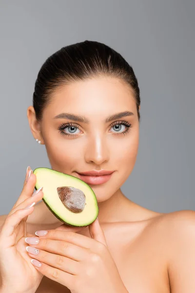 Woman with naked shoulders and avocado half isolated on grey — Stock Photo