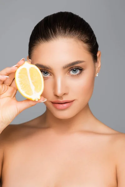 Woman with naked shoulders and lemon half isolated on grey — Stock Photo