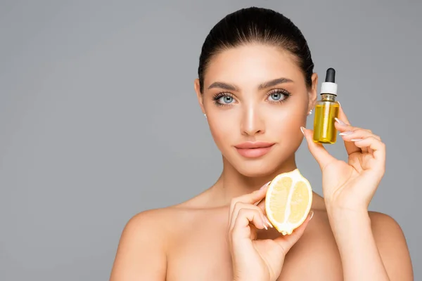 Mujer con suero y limón medio aislado en gris - foto de stock