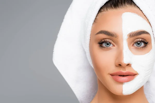 Woman with towel on head and clay mask on face isolated on grey — Stock Photo