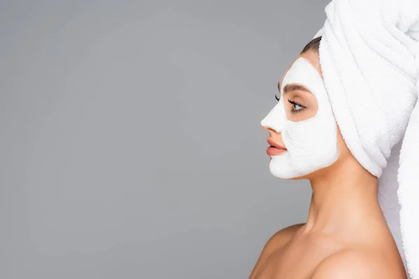 Profile of woman with towel on head and clay mask on face isolated on grey — Stock Photo