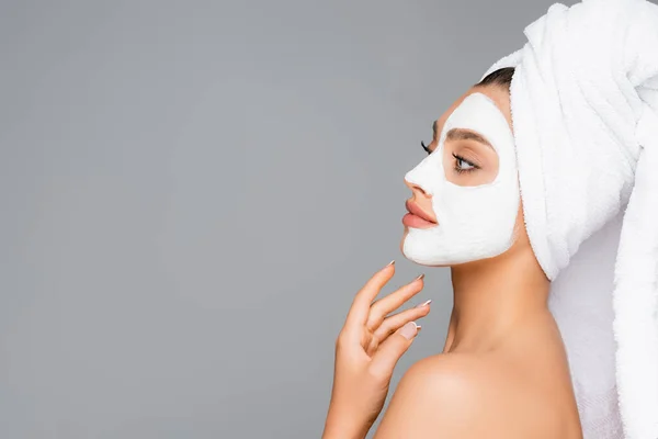 Side view of woman with towel on head and clay mask on face isolated on grey — Stock Photo