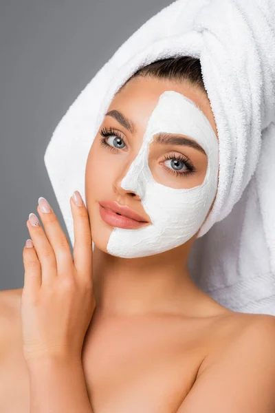 Woman with towel on head and clay mask on face isolated on grey — Stock Photo