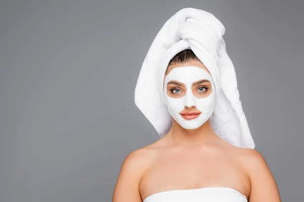 Femme avec serviette sur la tête et masque en argile sur le visage isolé sur gris — Photo de stock