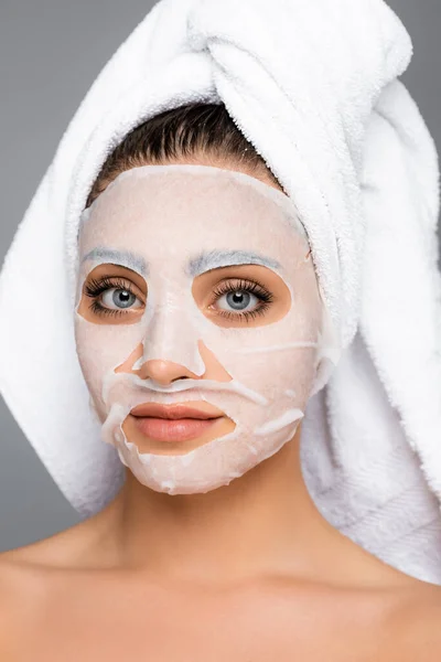 Женщина с полотенцем на голове и маска лист на лице изолированы на сером — стоковое фото