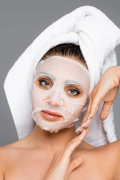 Woman with towel on head and mask sheet posing isolated on grey — Stock Photo