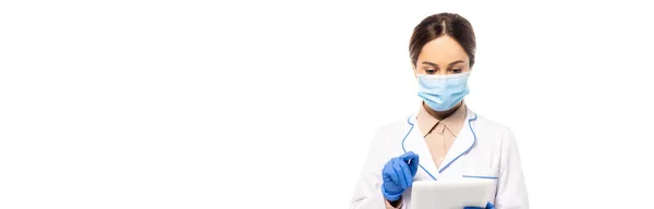 Горизонтальное изображение врача в медицинской маске и латексных перчатках с использованием цифровых таблеток, изолированных на белом — стоковое фото