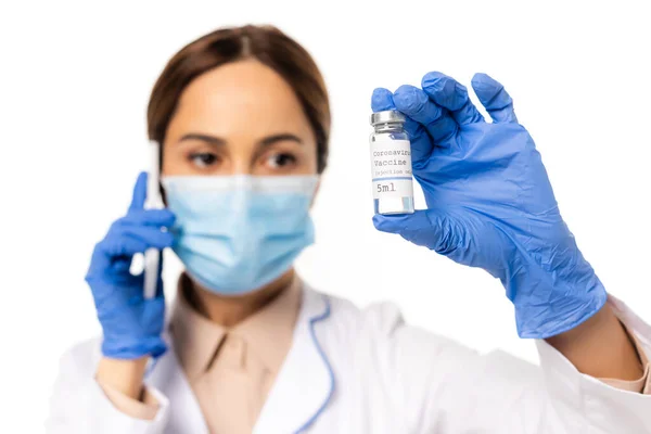 Selektiver Fokus des Arztes in medizinischer Maske und Latexhandschuhen, der auf dem Smartphone spricht und Coronavirus-Impfstoff isoliert auf weiß hält — Stockfoto