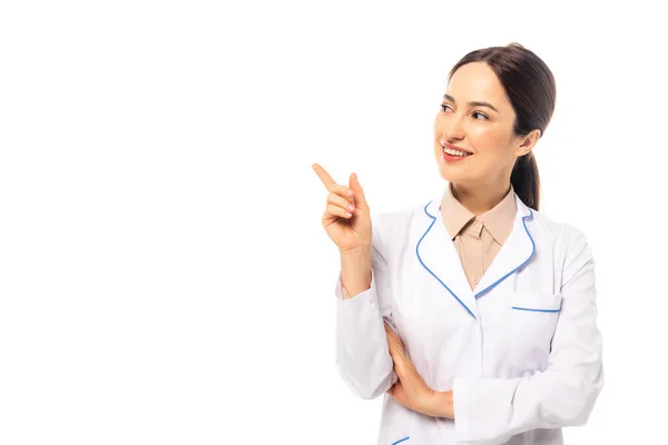 Médico sonriente de capa blanca apuntando con el dedo aislado sobre blanco - foto de stock