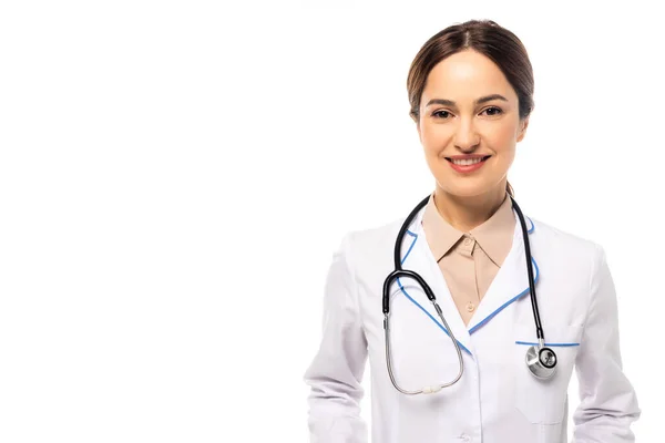 Médico positivo en bata blanca con estetoscopio mirando a la cámara aislada en blanco - foto de stock