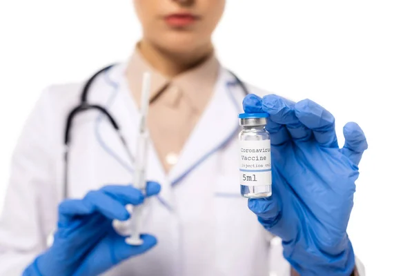 Vista ritagliata del medico in guanti di lattice che tengono il vaccino con coronavirus lettering e siringa isolata su bianco — Foto stock