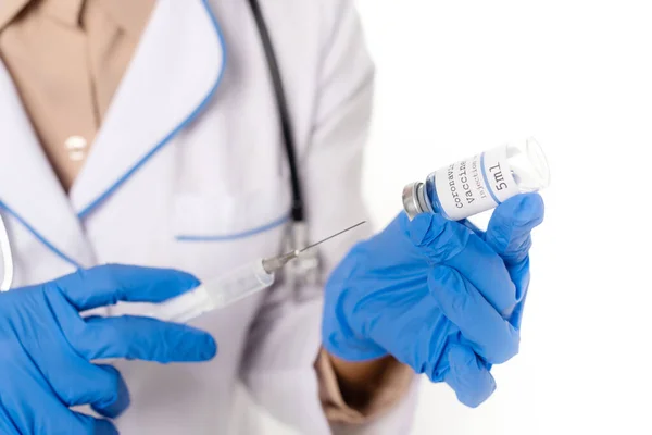 Vista recortada do médico em luvas de látex segurando frasco com vacina coronavírus e seringa isolada em branco — Fotografia de Stock