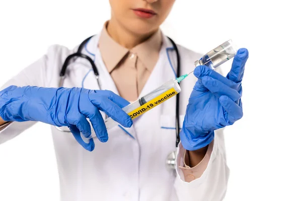 Vista recortada del médico recogiendo la vacuna en jeringa con letras covid-19 aisladas en blanco - foto de stock