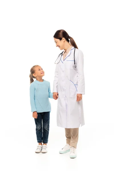 Pediatra agarrado de la mano y mirando al niño sobre fondo blanco - foto de stock