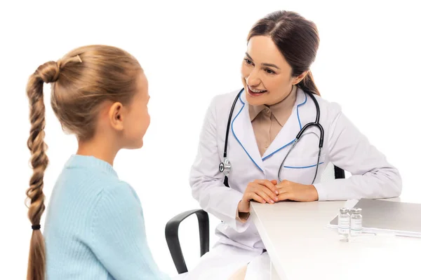 Selektiver Fokus des lächelnden Kinderarztes, der das Kind in der Nähe von Impfstoff und Papiermappe isoliert auf Weiß betrachtet — Stockfoto