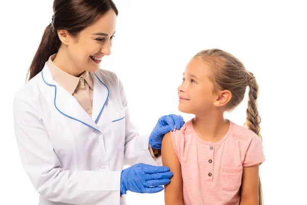 Médecin souriant en gants de latex regardant enfant isolé sur blanc — Photo de stock