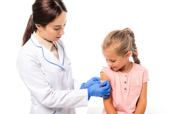 Médecin en gants de latex appliquant patch sur la main de la fille isolée sur blanc — Photo de stock