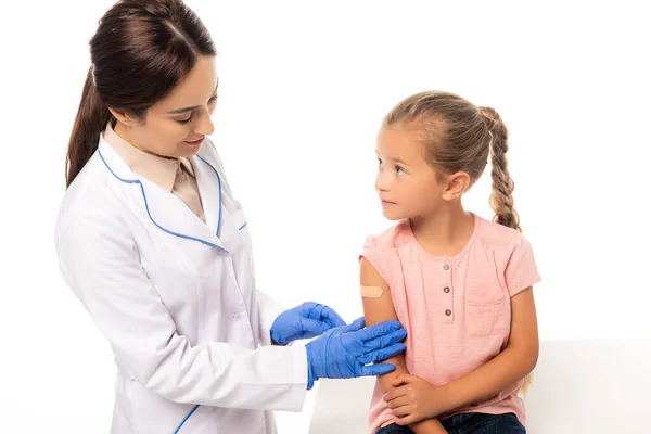 Médico tocando la mano de chica con parche aislado en blanco - foto de stock