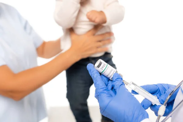 Foco seletivo do pediatra segurando seringa e vacina perto de pai e criança isolados em branco — Fotografia de Stock