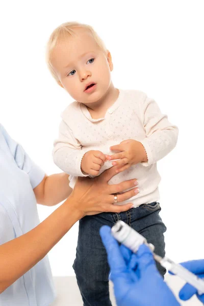 Foco seletivo do pai segurando menino perto pediatra com vacina e seringa isolada em branco — Fotografia de Stock