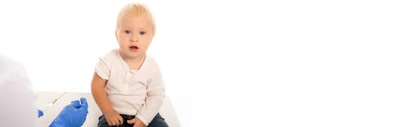 Panoramic shot of pediatrician holding syringe near toddler boy isolated on white — Stock Photo