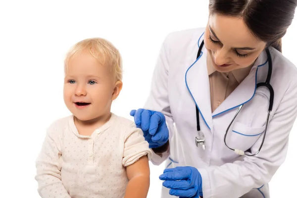 Pediatra em luvas de látex em pé perto do menino criança alegre isolado no branco — Fotografia de Stock