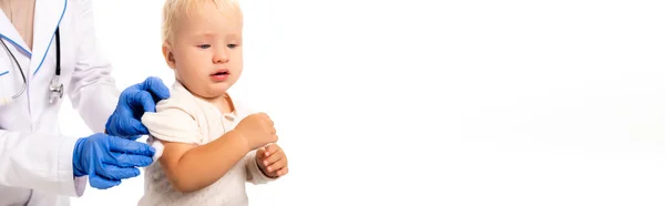 Horizontal crop of doctor in latex gloves holding cotton near hand of toddler boy isolated on white — Stock Photo