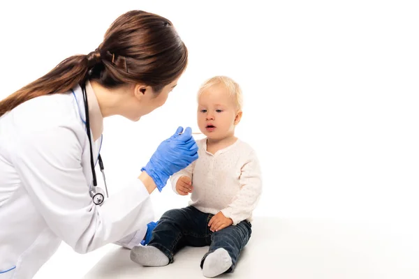 Выборочный фокус доктора, держащего палку рядом с малышом, изолированным на белом — стоковое фото
