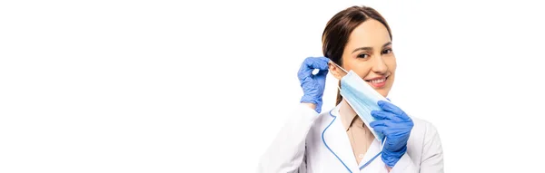 Sito web intestazione del medico positivo in guanti di lattice indossando maschera medica isolata su bianco — Foto stock