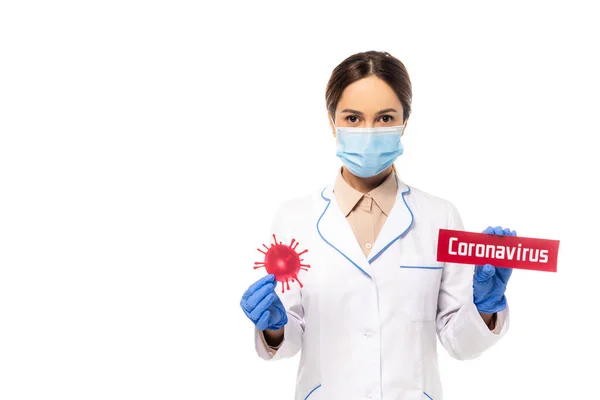 Médecin dans le masque médical tenant des bactéries et carte avec lettrage coronavirus isolé sur blanc — Photo de stock