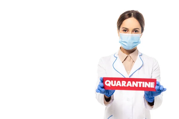 Médecin en masque médical et carte de maintien de manteau blanc avec lettrage de quarantaine isolé sur blanc — Photo de stock