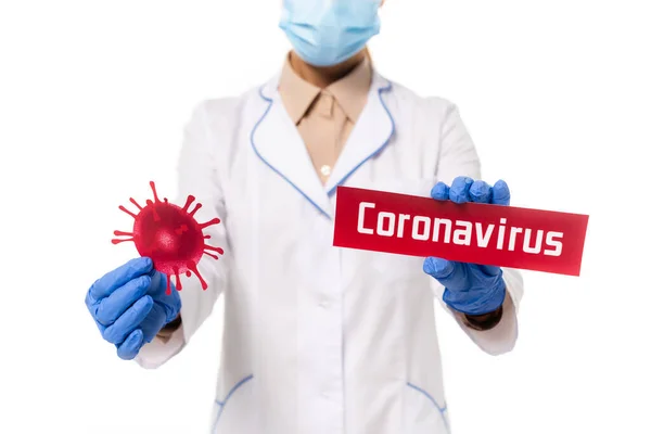 Vista ritagliata del medico in possesso di carta con coronavirus lettering e batteri isolati su bianco — Foto stock