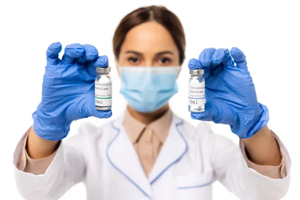 Enfoque selectivo del médico en guantes de látex que sostienen frascos con letras de vacuna contra el coronavirus aisladas en blanco - foto de stock