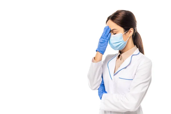 Médecin en masque médical et gants en latex touchant le front isolé sur blanc — Photo de stock