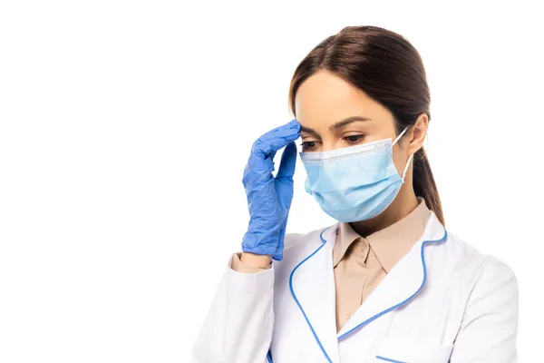 Médico en máscara médica y guante de látex tocando la frente aislado en blanco - foto de stock