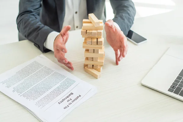 Vista ritagliata del fallimento con le mani vicino blocchi gioco torre di legno, seduto sul posto di lavoro — Foto stock