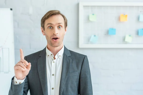 Front view of excited businessman with idea gesture, looking at camera on blurred background — Stock Photo