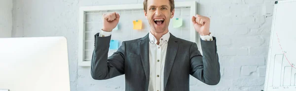 Emocionado hombre de negocios con gesto ganador mirando a la cámara, mientras que de pie con organizador de malla en el fondo, pancarta - foto de stock